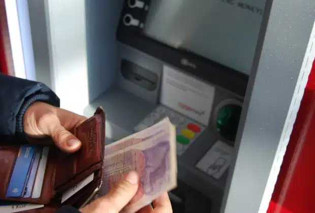 person holding brown leather wallet and banknotes